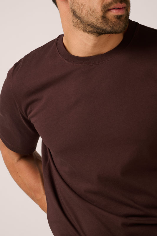 Man wearing a plain brown t-shirt against a neutral background