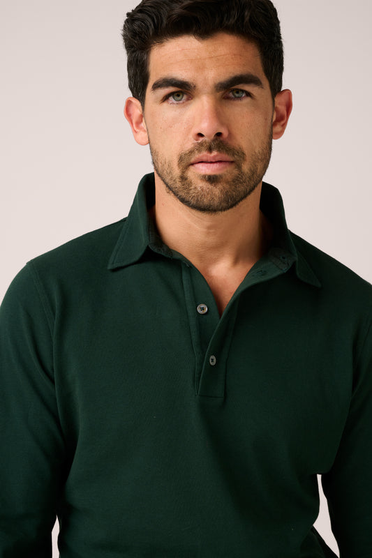 Man wearing a dark green polo shirt against a plain background