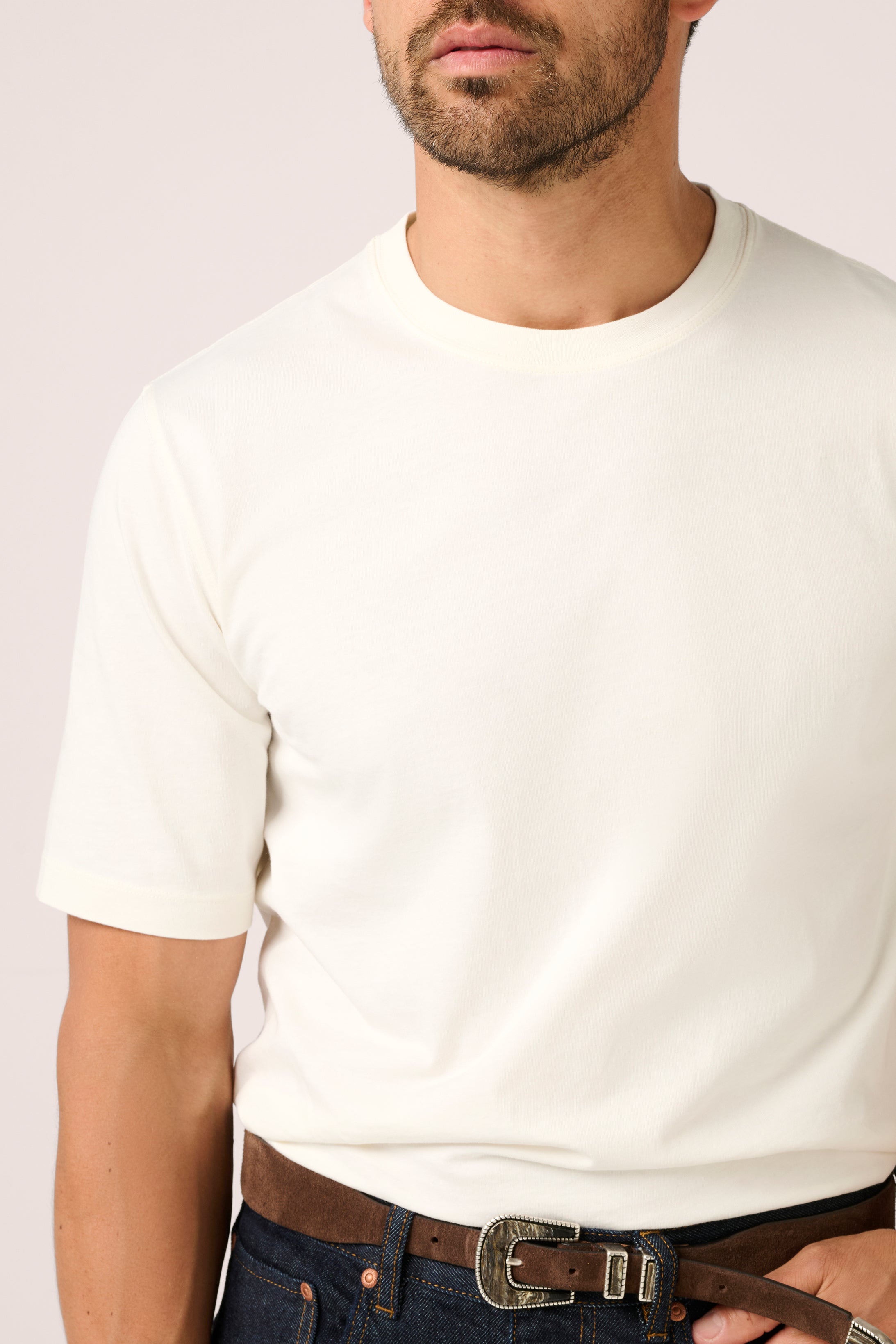 Man wearing a plain white t-shirt with a neutral background