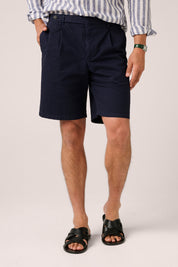 Person wearing navy shorts and a striped shirt on a plain background