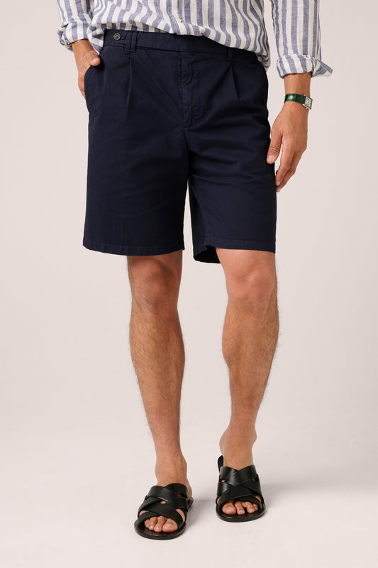 Person wearing navy shorts and a striped shirt on a plain background