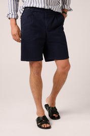 Person wearing navy shorts and a striped shirt on a plain background
