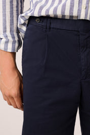 Navy pants worn with a striped shirt on a neutral background