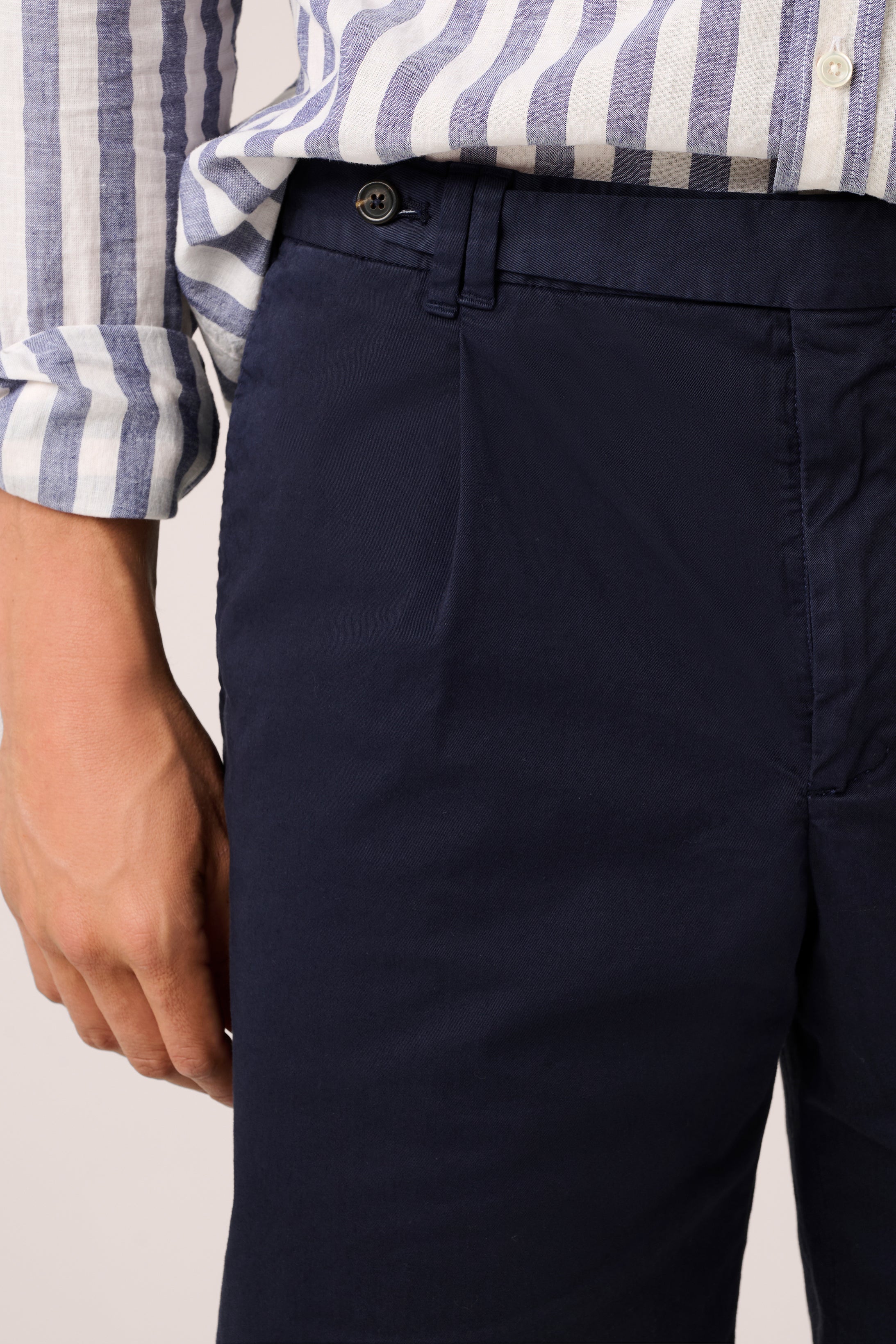 Navy pants worn with a striped shirt on a neutral background
