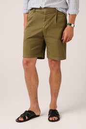 Person wearing olive green shorts on a plain background