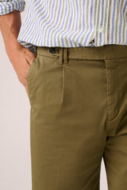 Brown pants worn with a striped shirt on a plain background
