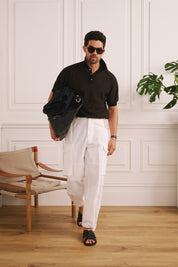 Man holding a black bag in a room with wooden floor and white walls