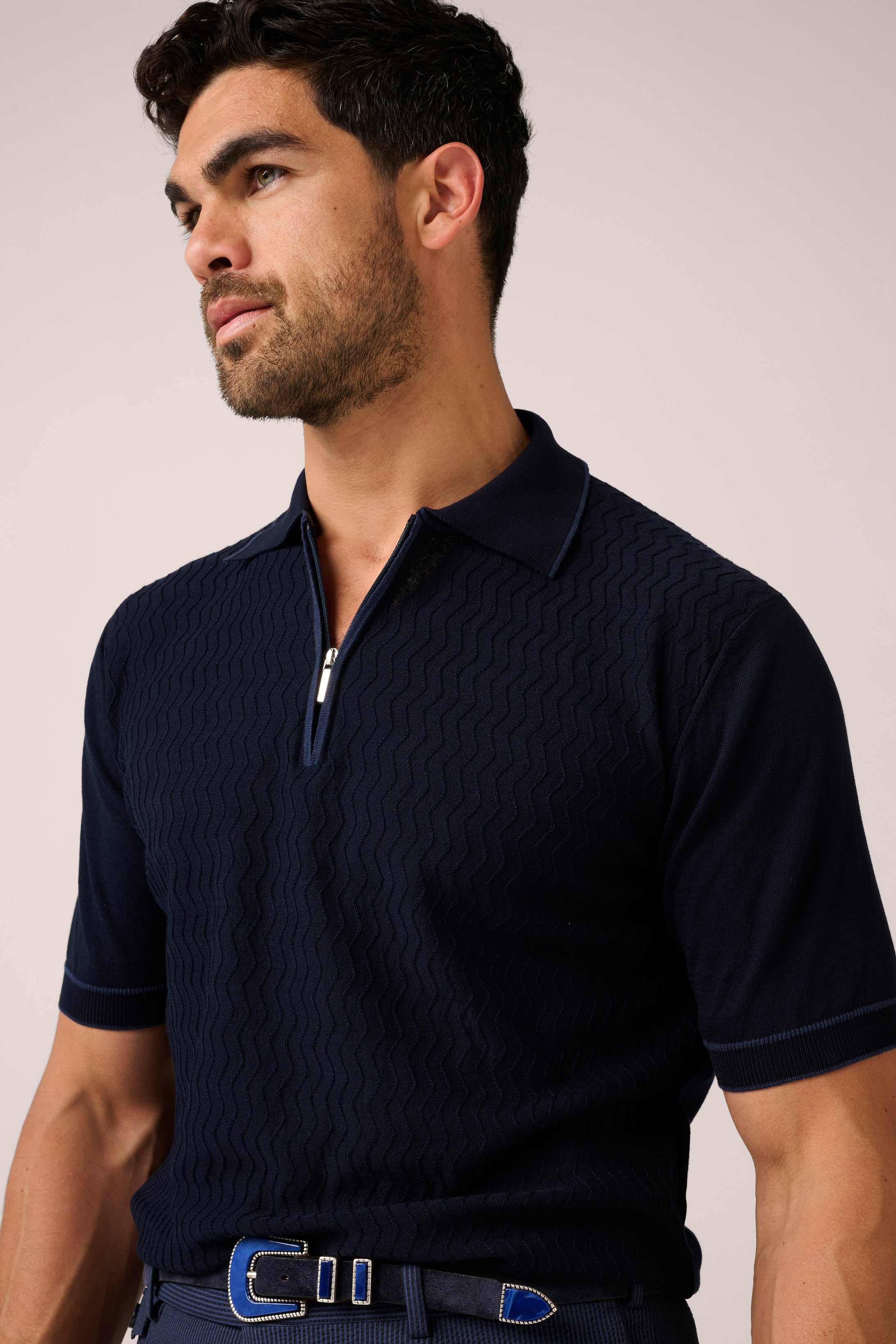 Man wearing a navy blue textured polo shirt against a plain background