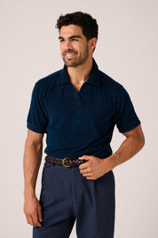 Man wearing a navy polo shirt and pants on a plain background