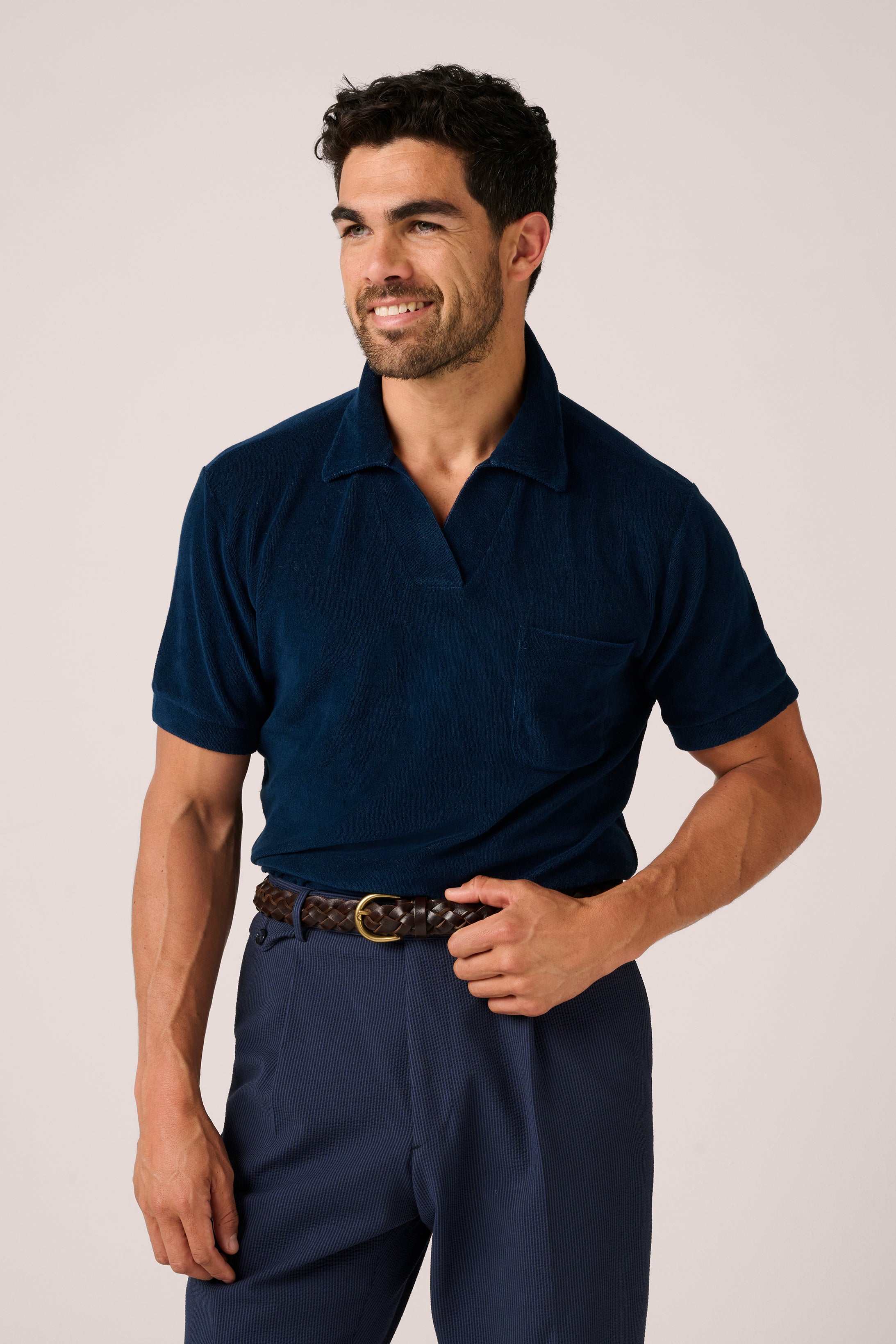 Man wearing a navy polo shirt and pants on a plain background