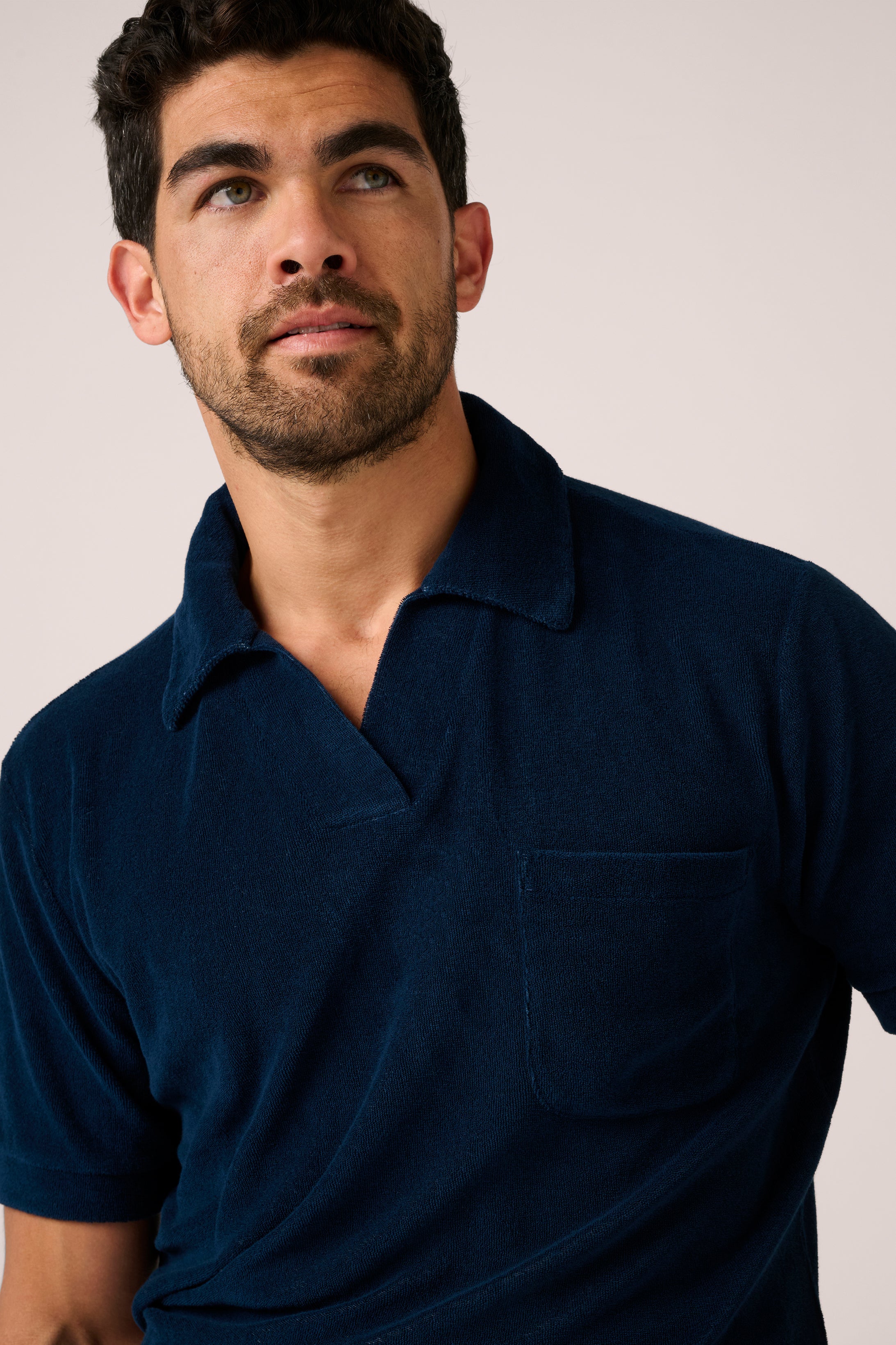 Man wearing a navy blue polo shirt against a plain background