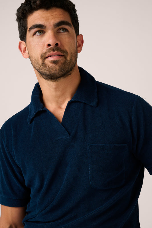 Man wearing a navy blue polo shirt against a plain background