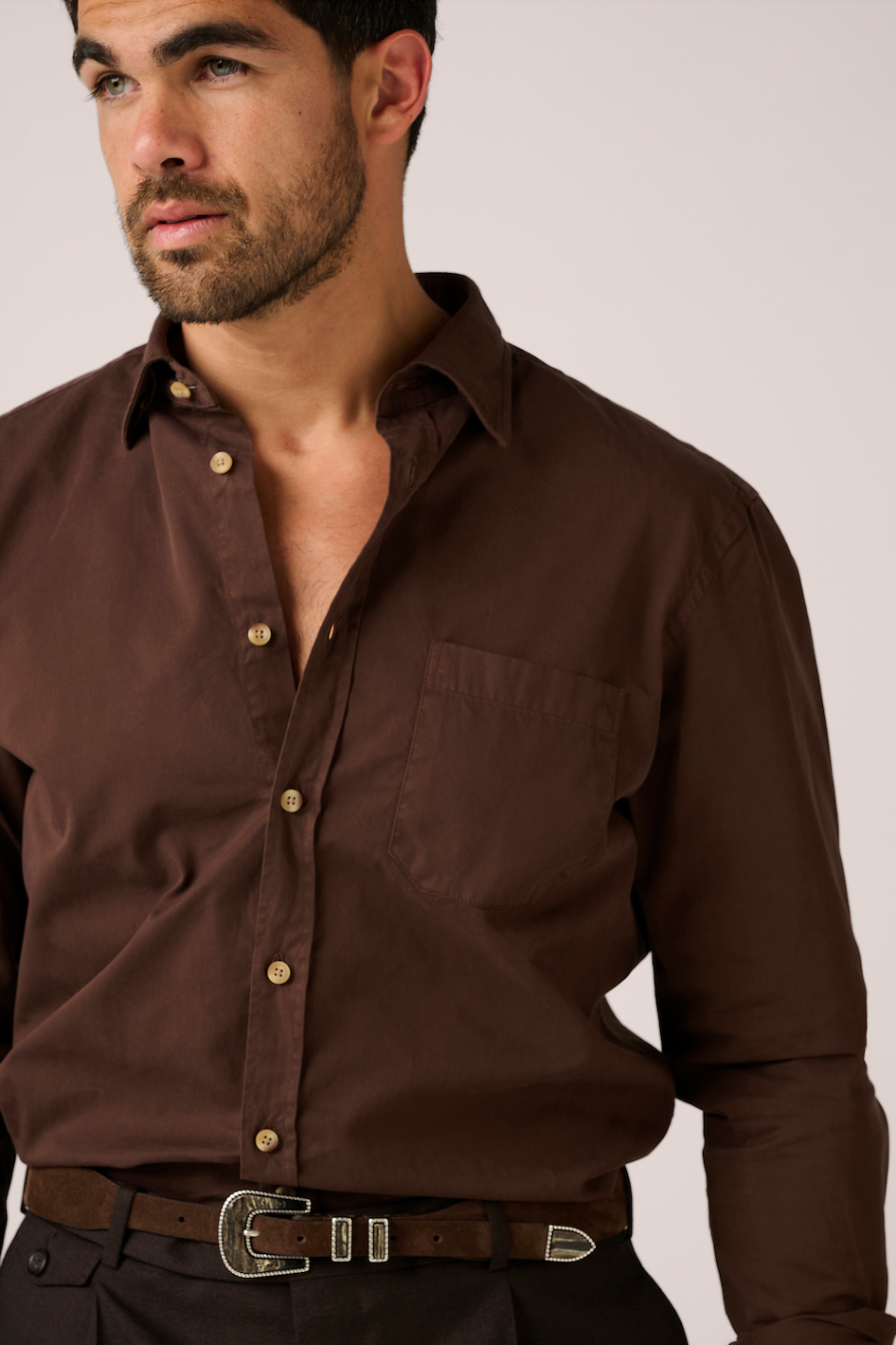 Man wearing a brown shirt with a plain background