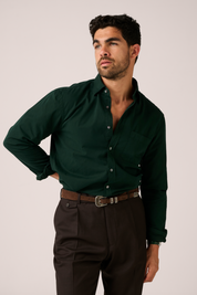Man wearing a dark green shirt and brown pants against a plain background