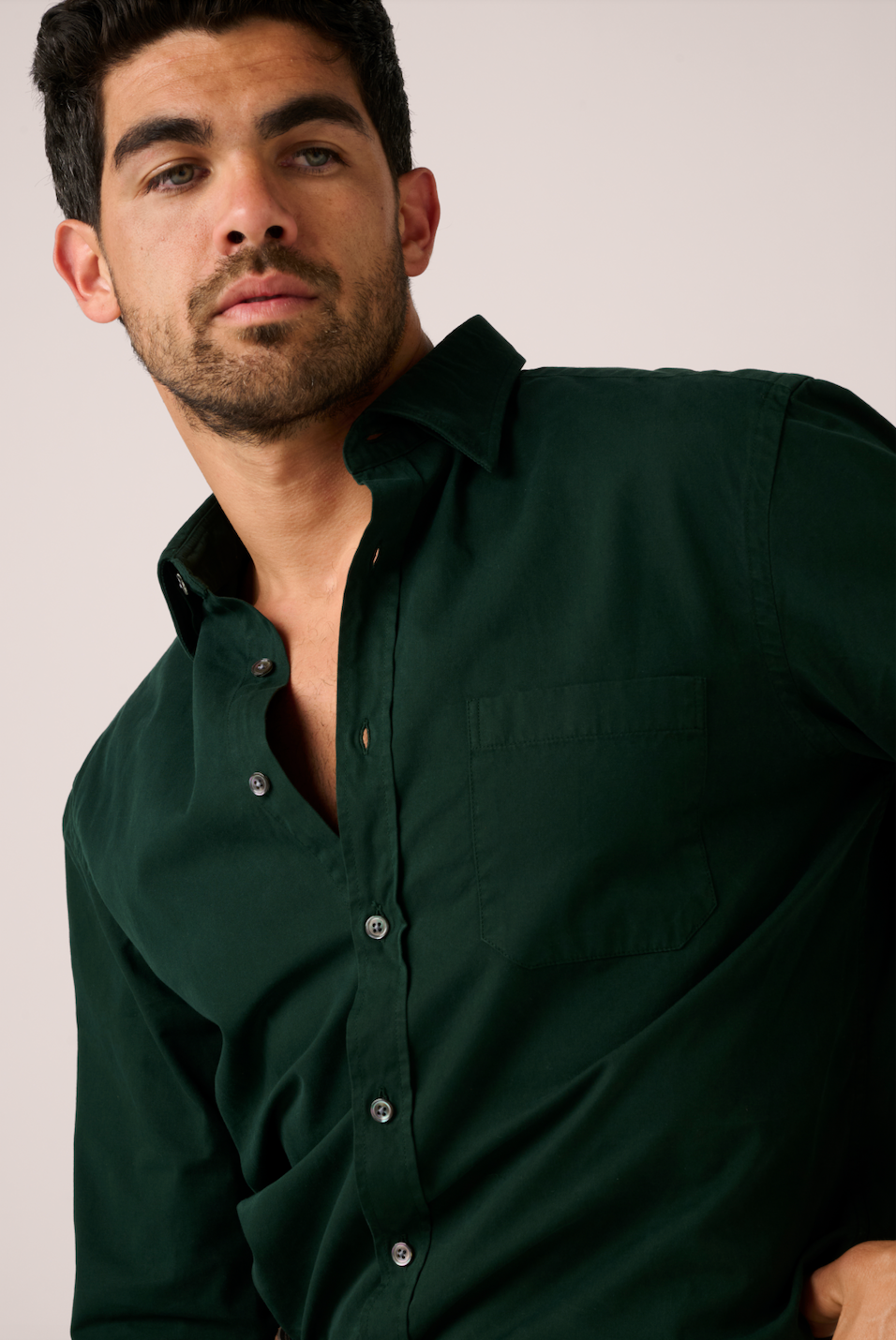 Man wearing a dark green shirt against a plain background