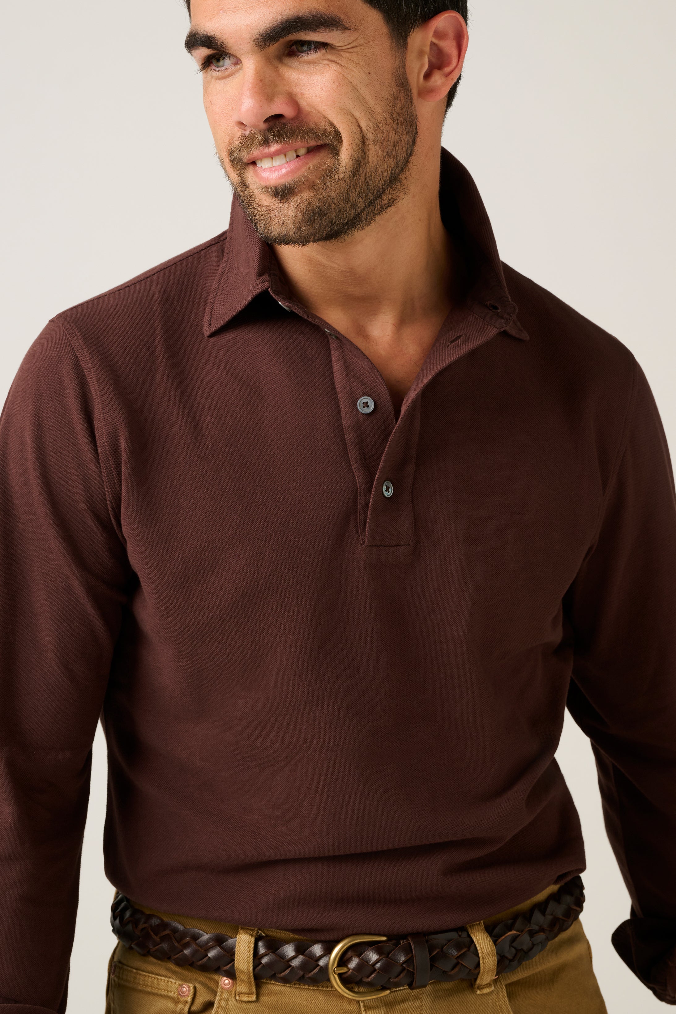 Man wearing a brown long-sleeve polo shirt against a plain background