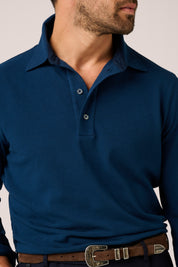 Man wearing a blue long-sleeve polo shirt with a neutral background