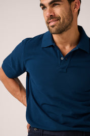 Man wearing a blue polo shirt against a plain background