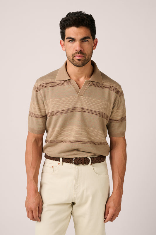 Man wearing a beige striped polo shirt and light-colored pants on a plain background