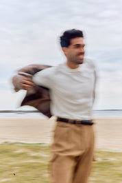 Man holding a brown jacket with a blurred background