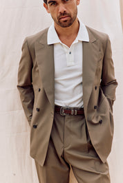 Man wearing a beige suit with a white shirt against a neutral background